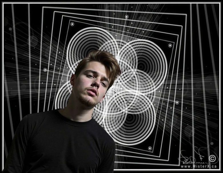 Handsome young man is seen posing in front of a geometric digital drawing.